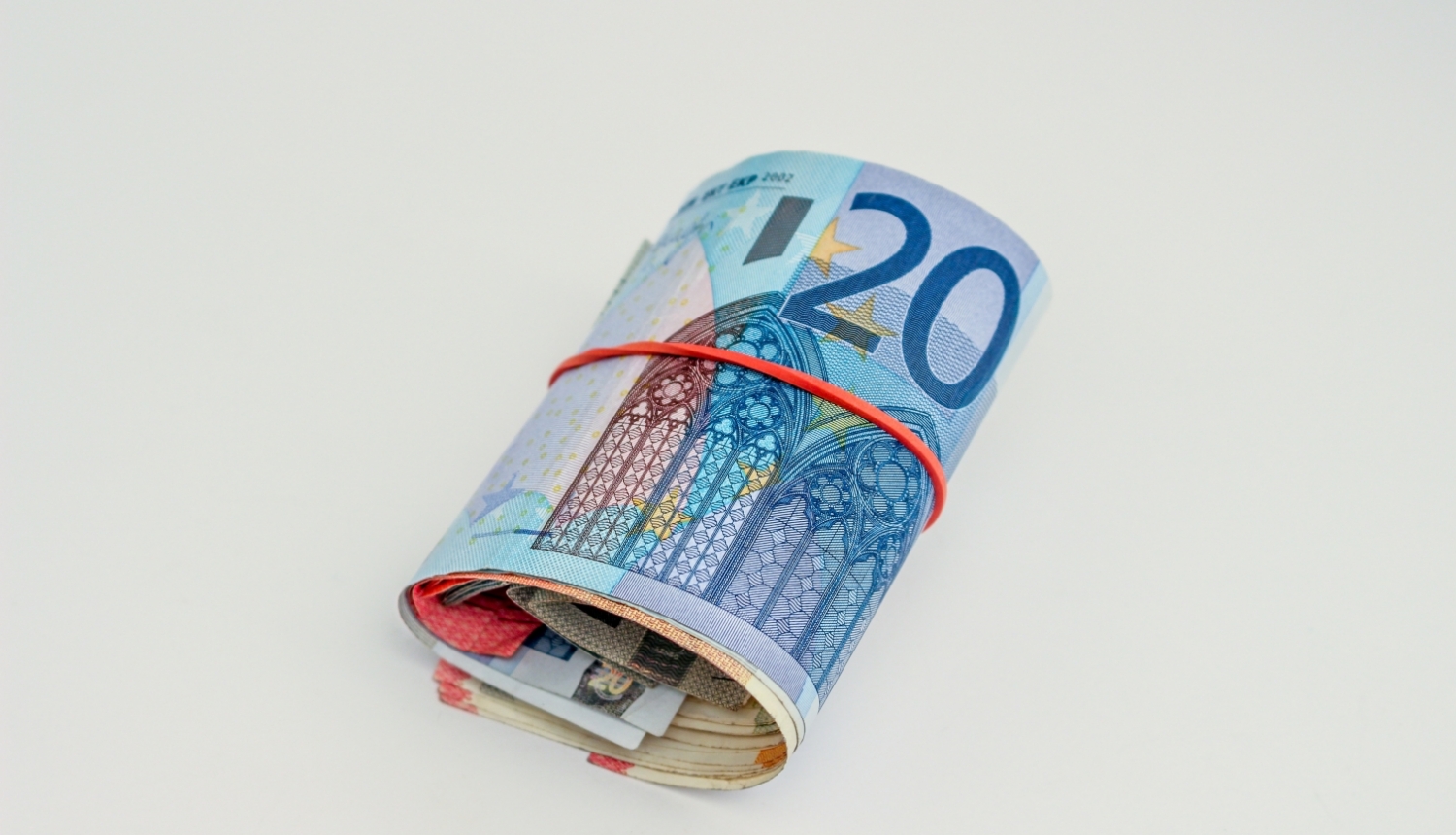 20 eiro banknote sarullēta kopā ar citu nominālu banknotēm un aplikta apkārt sarkana gumija